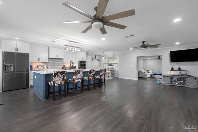 a open kitchen with stainless steel appliances granite countertop a refrigerator dining table and chairs with wooden floor