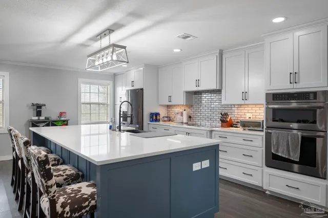 a kitchen with kitchen island granite countertop a sink cabinets stainless steel appliances and a counter top space