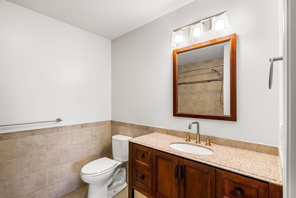 39 Fayette Street, Unit 403 Quincy, MA 02171 - Photo 15 of 24 a bathroom with a granite countertop sink mirror vanity and toilet