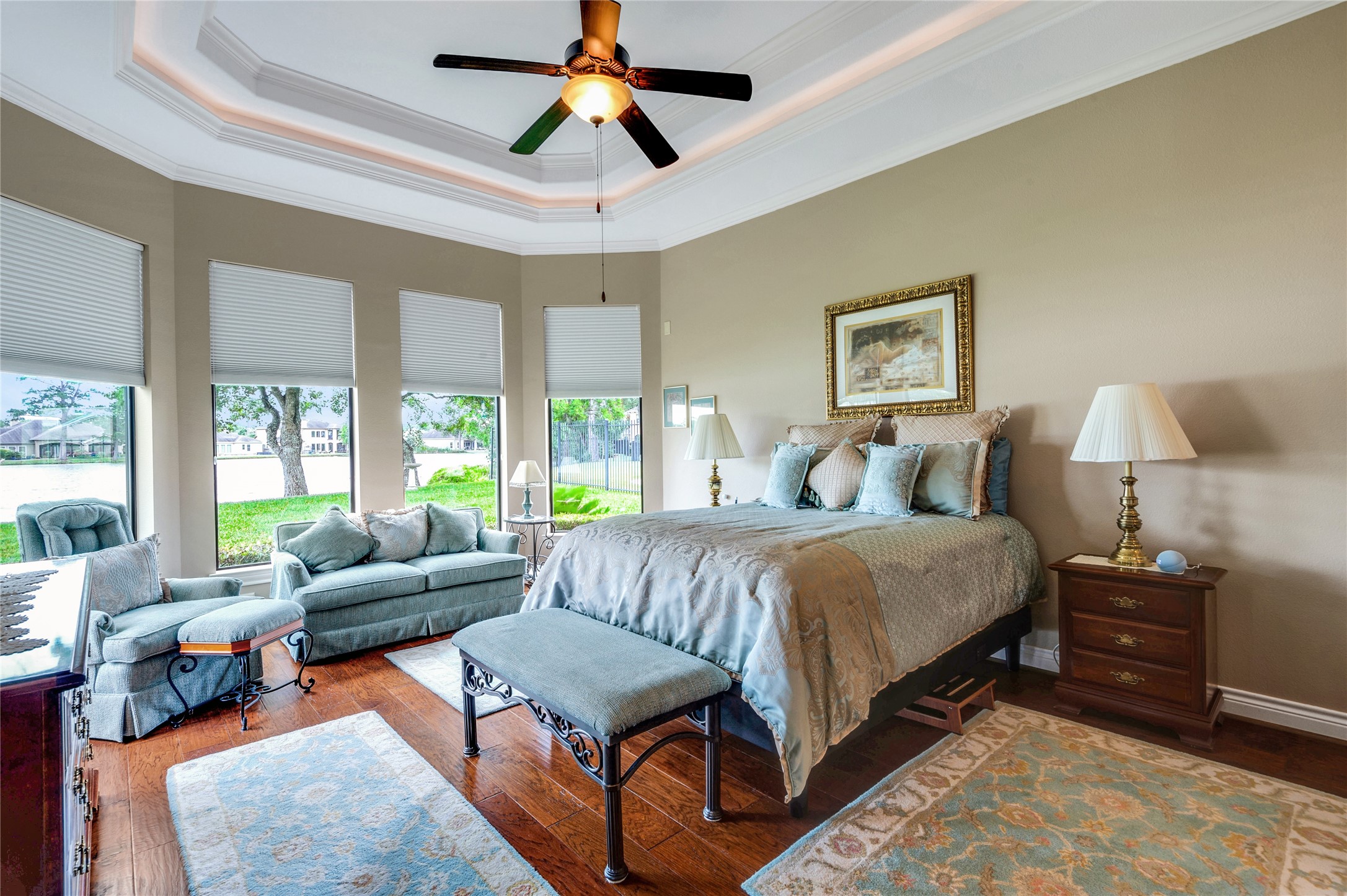 6119 Lofty Lane Spring, TX 77379 - Photo 28 of 40 Bright and spacious bedroom with large windows offering lake views. Features a cozy sitting area, elegant tray ceiling with fan, and hardwood floors. Perfect for relaxation and comfort.