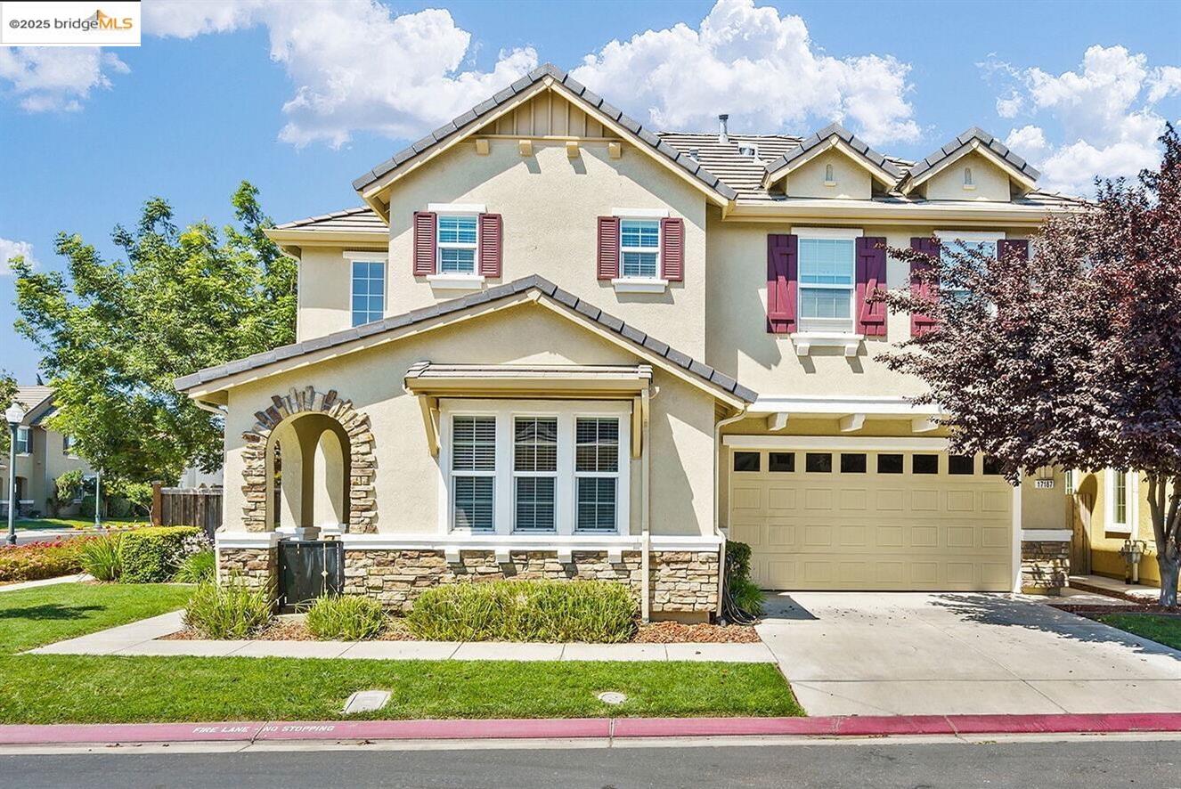 a view of a white house with a small yard and large trees