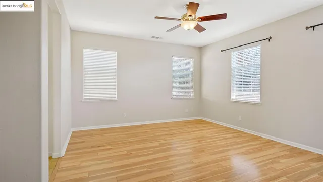 a view of a room with wooden floor and ceiling fan