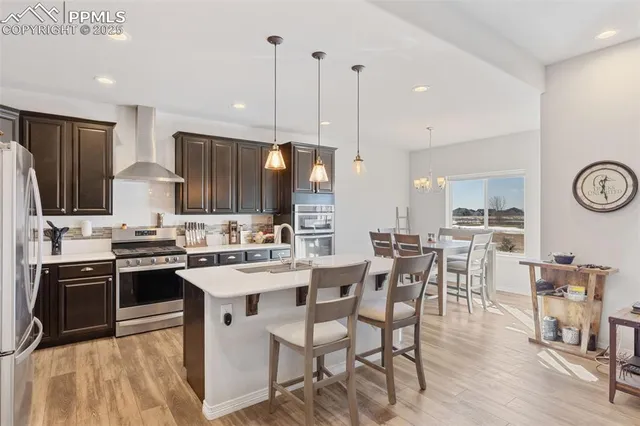 a kitchen with stainless steel appliances kitchen island granite countertop a sink a stove a refrigerator and island with wooden floor