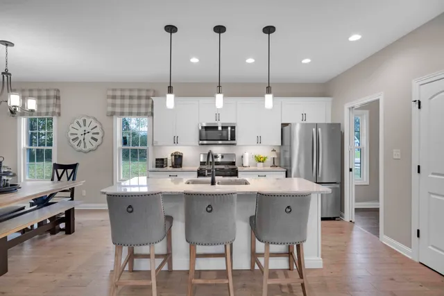 a kitchen with stainless steel appliances a sink a stove a refrigerator a center island and cabinets
