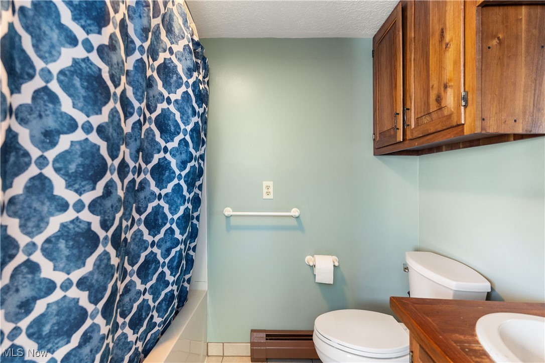 5070 Russell Road Andover, OH 44003 - Photo 18 of 25 Full bathroom with vanity, tile patterned flooring, toilet, a textured ceiling, and a baseboard radiator