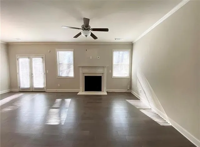 an empty room with wooden floor fireplace and windows