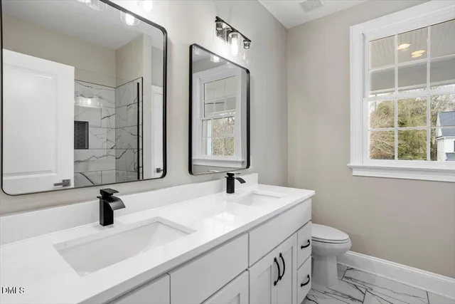 a bathroom with a double vanity sink toilet and a mirror