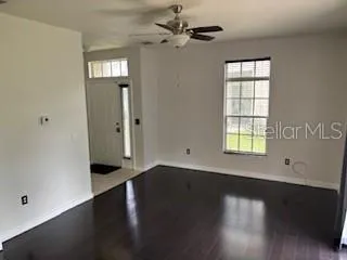 an empty room with wooden floor closet and windows