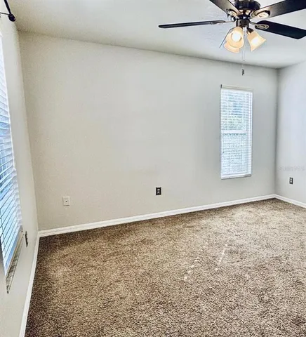 an empty room with a window and a fan