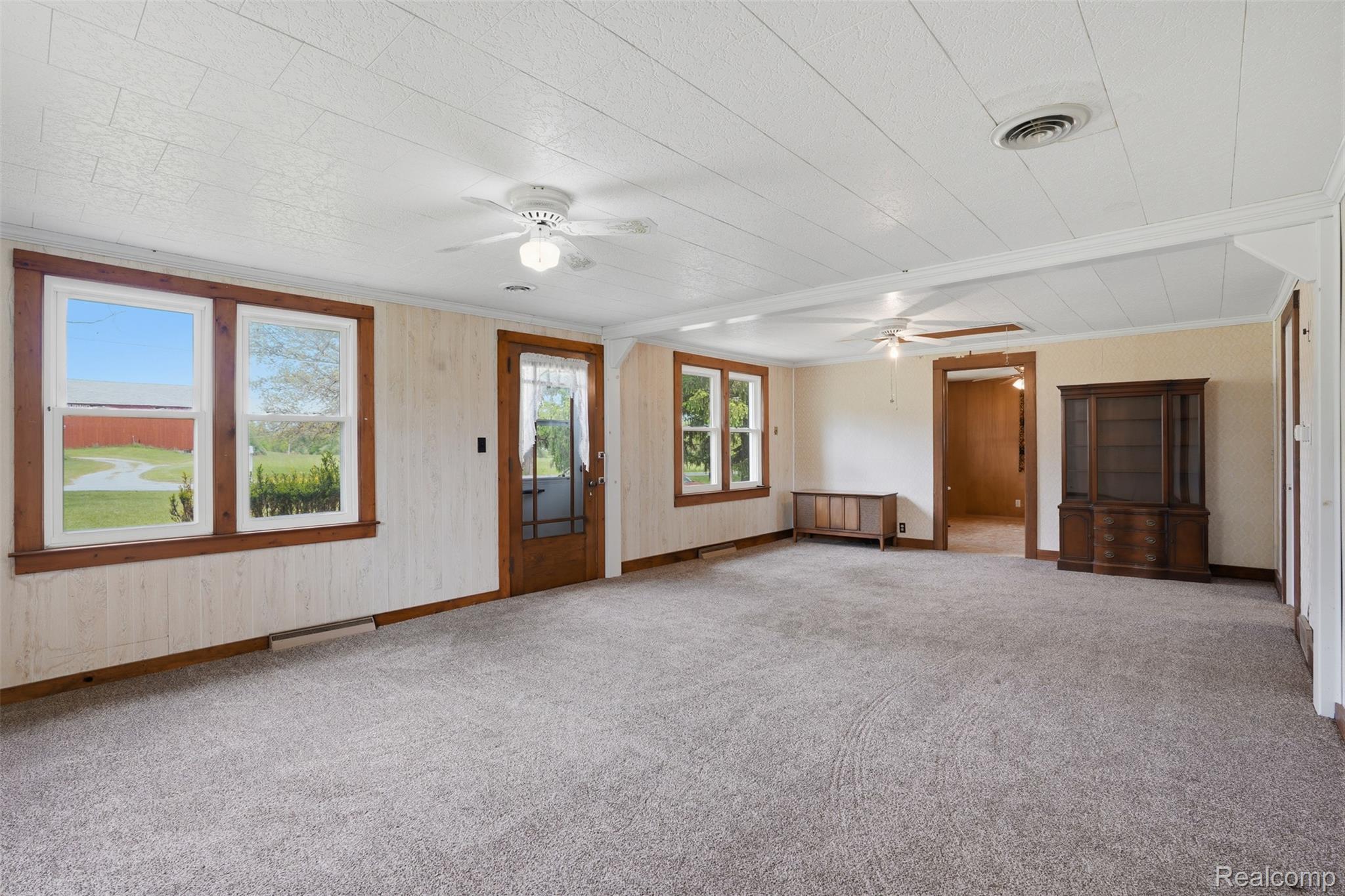 3405 West Coon Lake Road Howell, MI 48843 - Photo 3 of 36 Unfurnished living room with ornamental molding, carpet flooring, and a ceiling fan