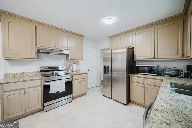 a kitchen with stainless steel appliances granite countertop a stove a refrigerator and a sink with cabinets