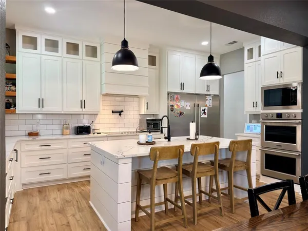 a kitchen with kitchen island granite countertop a table chairs microwave and cabinets