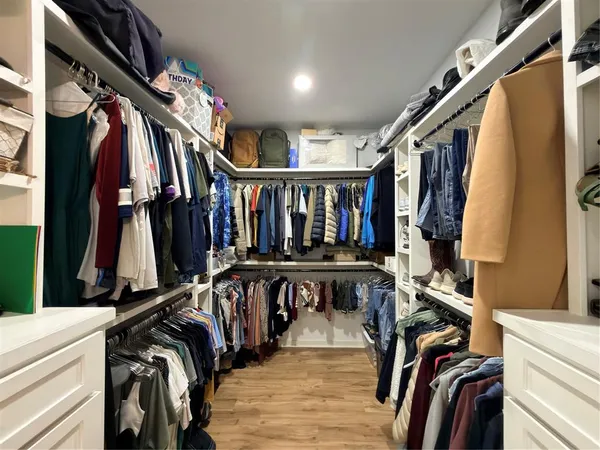 a view of walk in closet with clothes and shoes