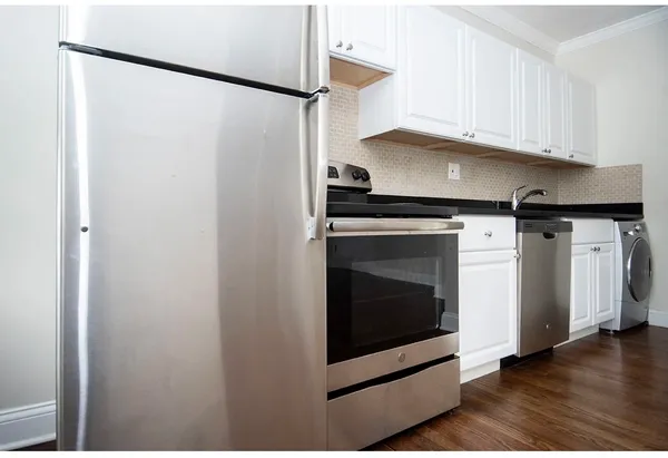 a kitchen with stainless steel appliances a refrigerator a stove and white cabinets