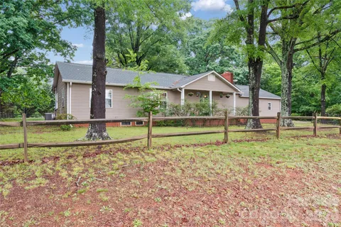 a view of a house with a yard and a large tree