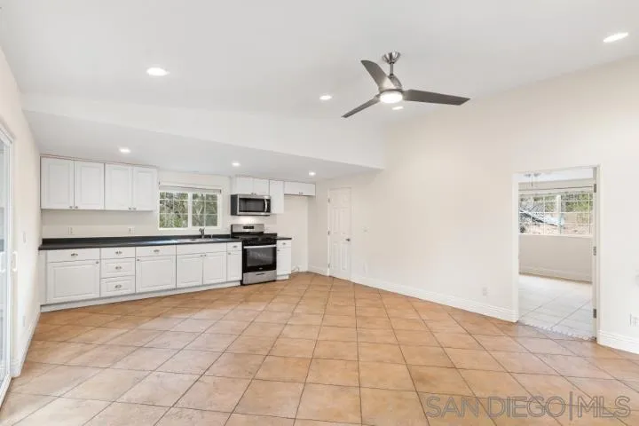 3253 Yucca Terrace Fallbrook, CA 92028 - Photo 55 of 62 a large white kitchen with kitchen island a stove a sink a refrigerator and white cabinets with wooden floor