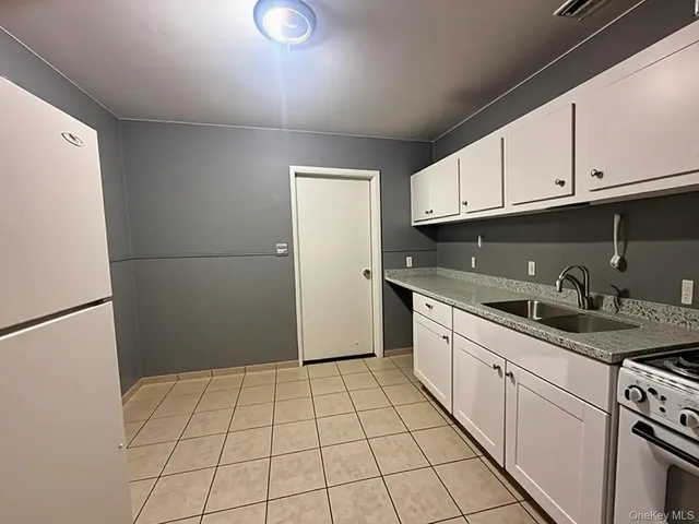 a kitchen with granite countertop a sink a stove a refrigerator and cabinets