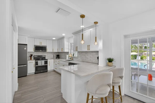 a kitchen with stainless steel appliances granite countertop a refrigerator sink and white cabinets