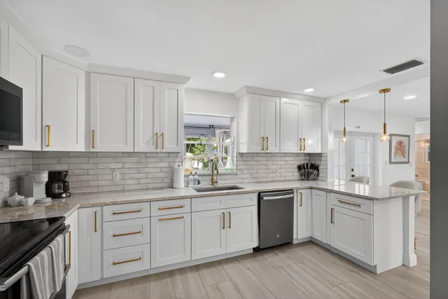 a kitchen with white cabinets and sink