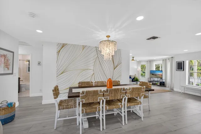 a kitchen with stainless steel appliances granite countertop a stove top oven a sink dishwasher a refrigerator and a dining table with wooden floor