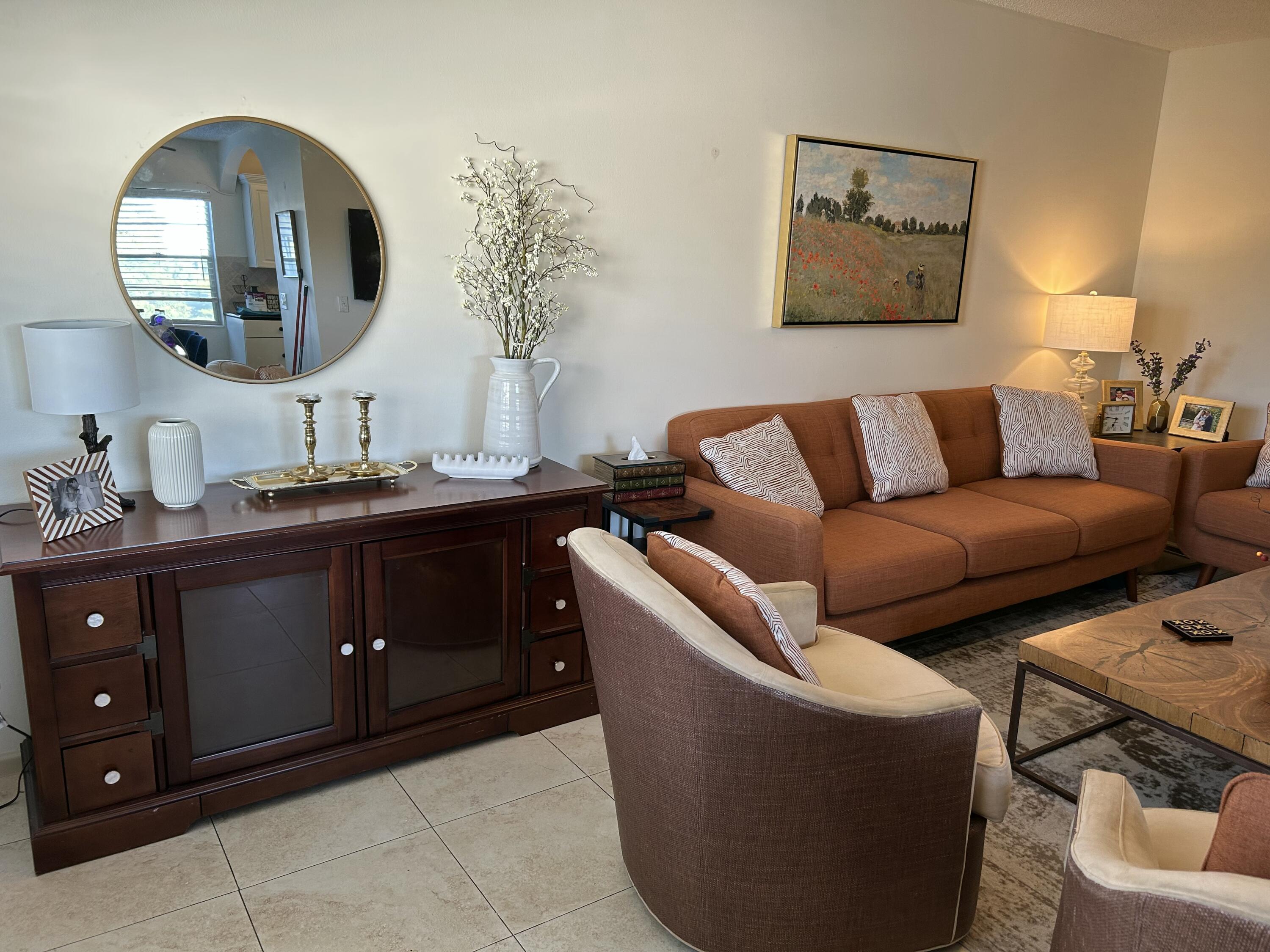 243 Suffolk F Boca Raton, FL 33434 - Photo 2 of 12 a living room with couches a mirror and a potted plant on the dresser