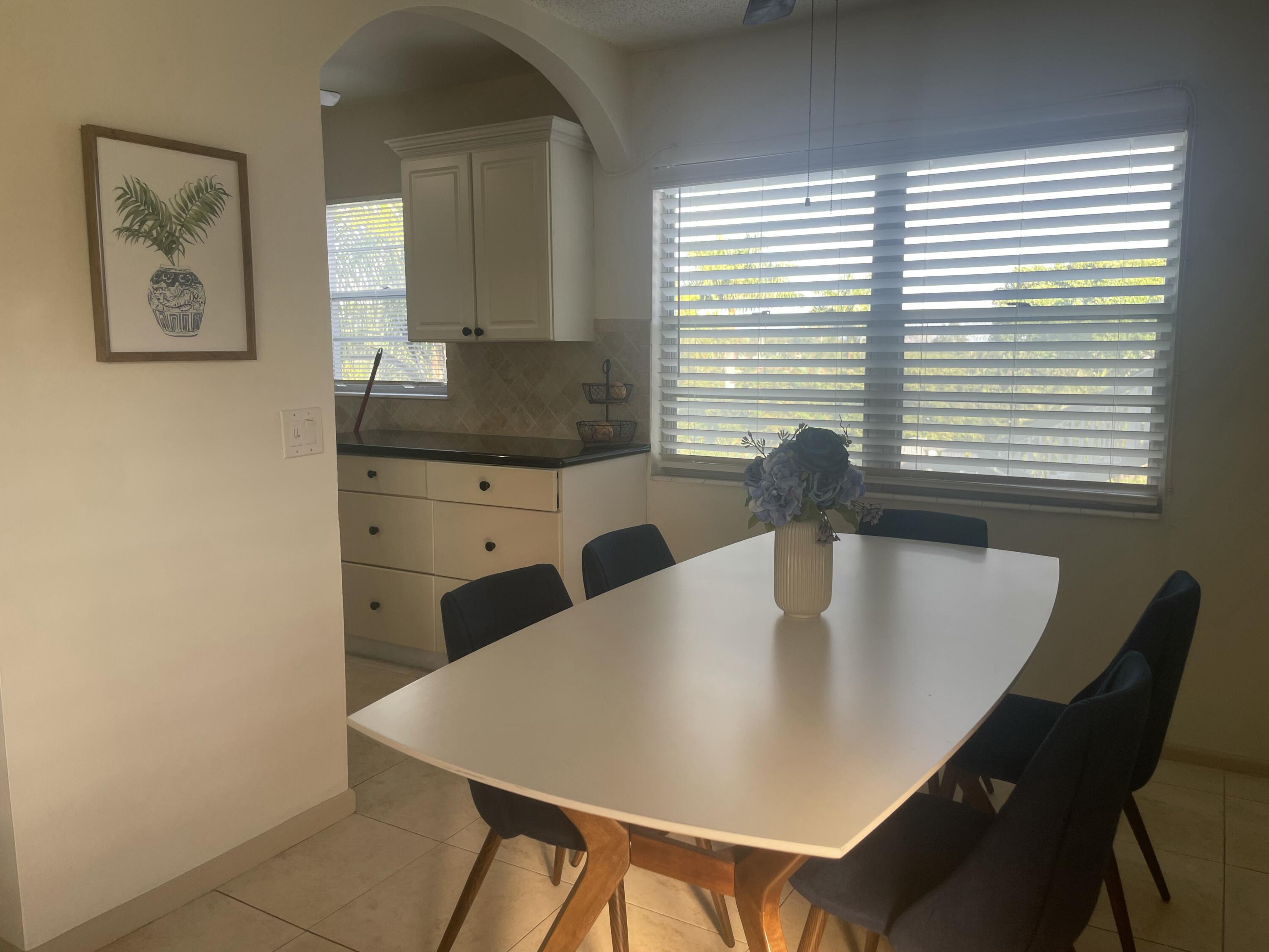 243 Suffolk F Boca Raton, FL 33434 - Photo 6 of 12 a kitchen with a table chairs and a refrigerator