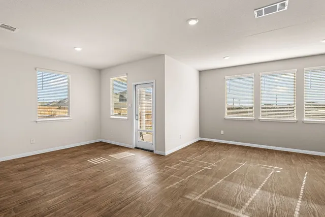 a view of an empty room with window and wooden floor