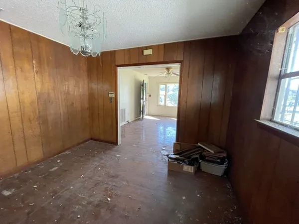 an empty room with a mirror and windows