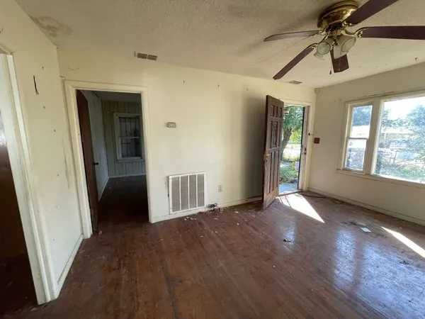 an empty room with wooden floor and windows