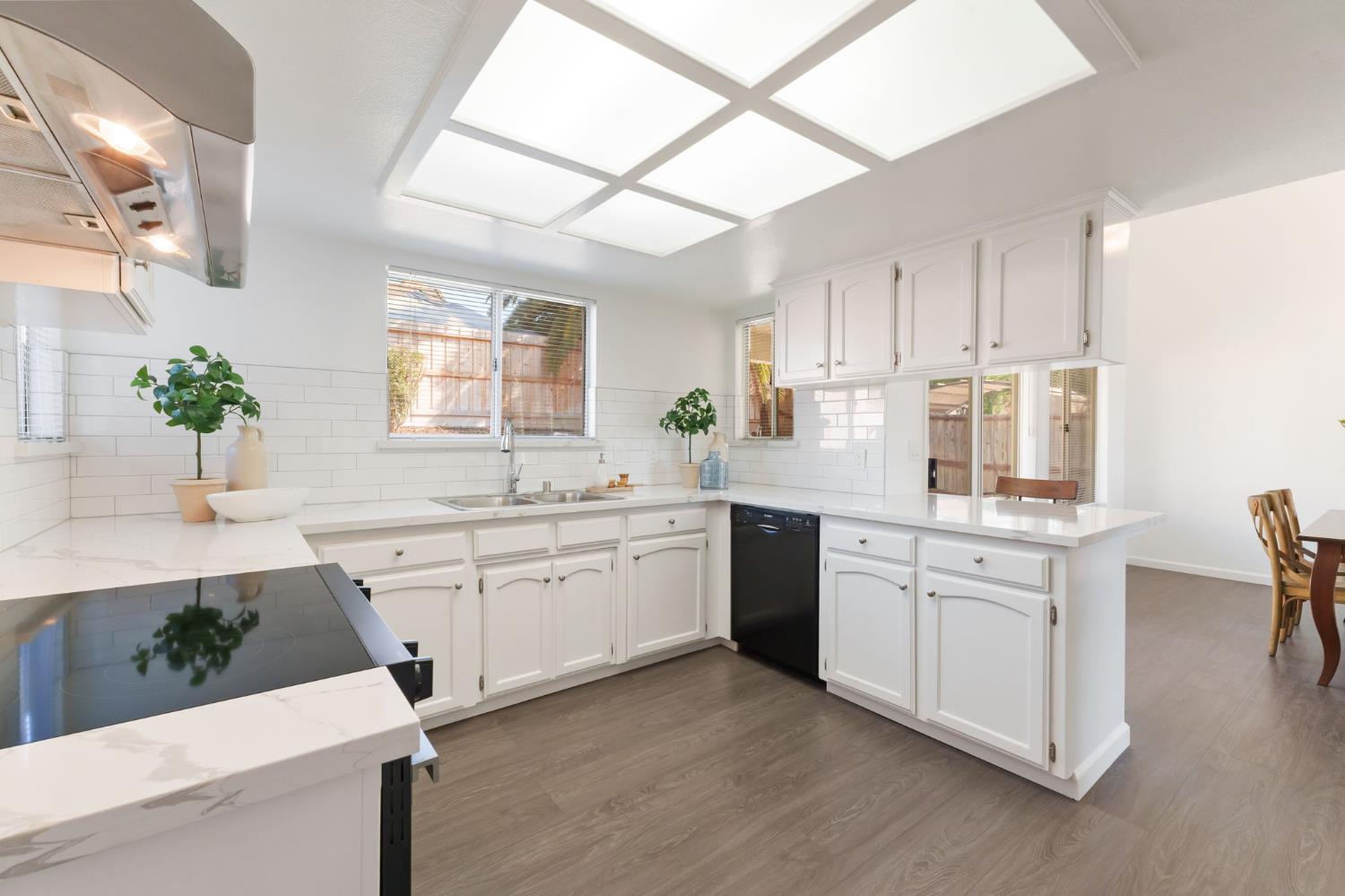 9342 North Archie Avenue Fresno, CA 93720 - Photo 12 of 36 a kitchen with granite countertop white cabinets a sink a window and stainless steel appliances