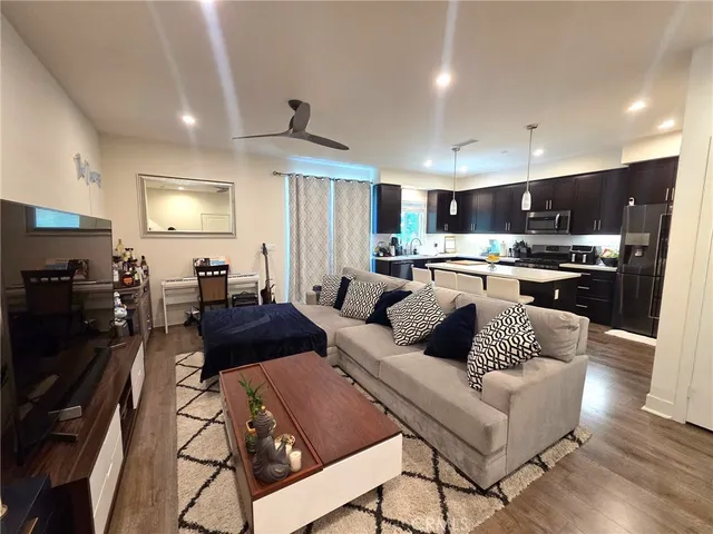 a living room with stainless steel appliances furniture and a kitchen view