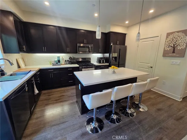 a kitchen with granite countertop a dining table chairs and refrigerator