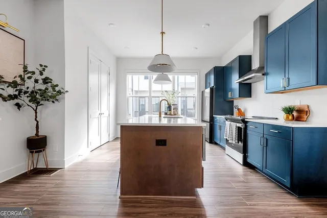 a kitchen with stainless steel appliances granite countertop a refrigerator a sink dishwasher a dining table and chairs with wooden floor