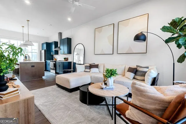 a living room with furniture potted plant and kitchen view