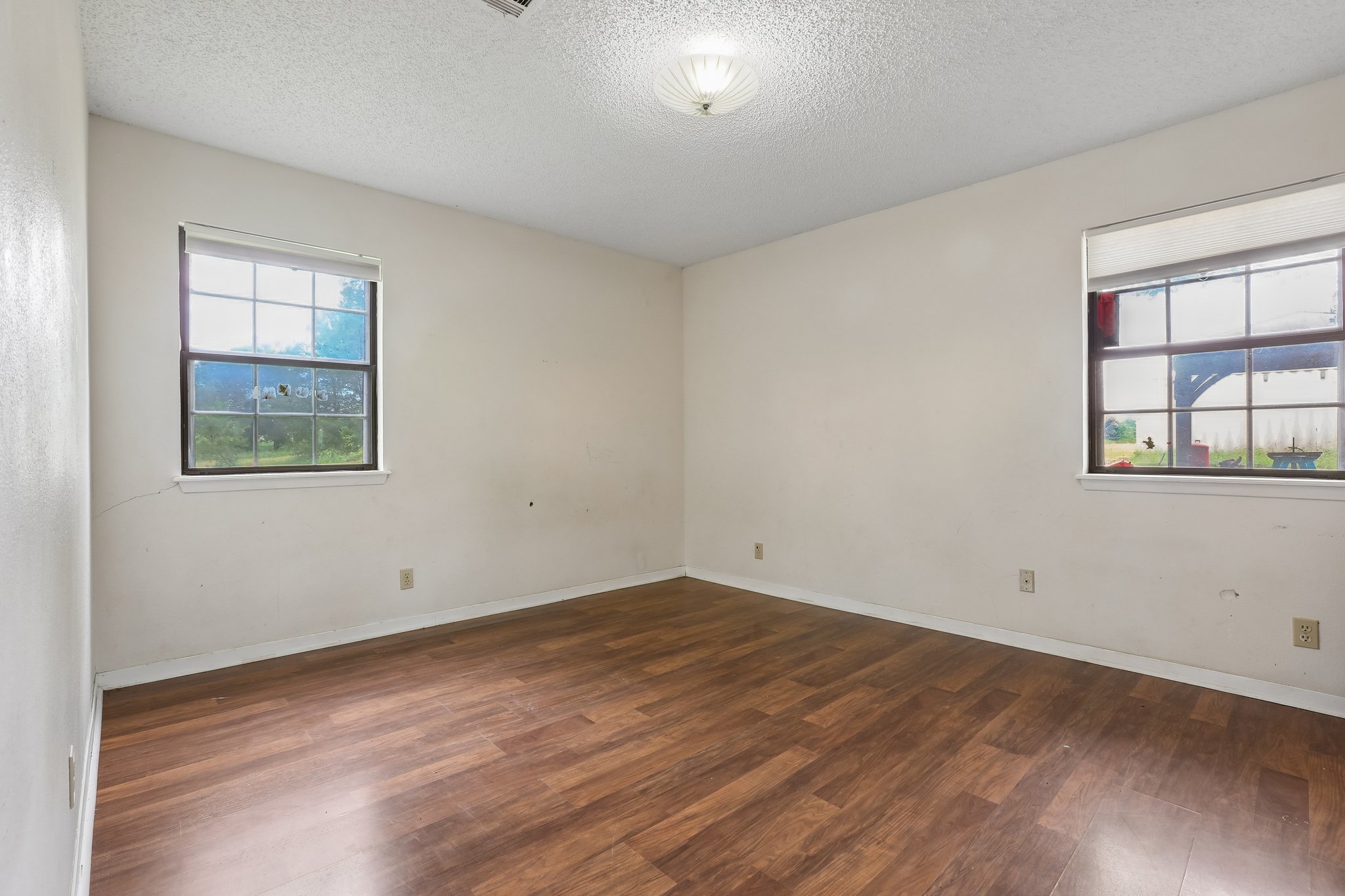 406 Monkey Road Elgin, TX 78621 - Photo 23 of 39 Spacious room featuring wood-finish flooring, two windows with blinds, light-toned walls, and a ceiling-mounted light fixture