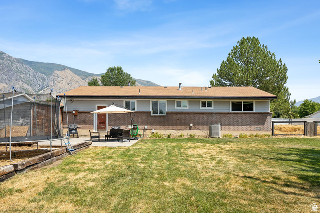 495 North 250 West Springville, UT 84663 - Photo 29 of 35 Back of property featuring a trampoline, brick siding, a mountain view, a fenced backyard, and a patio area