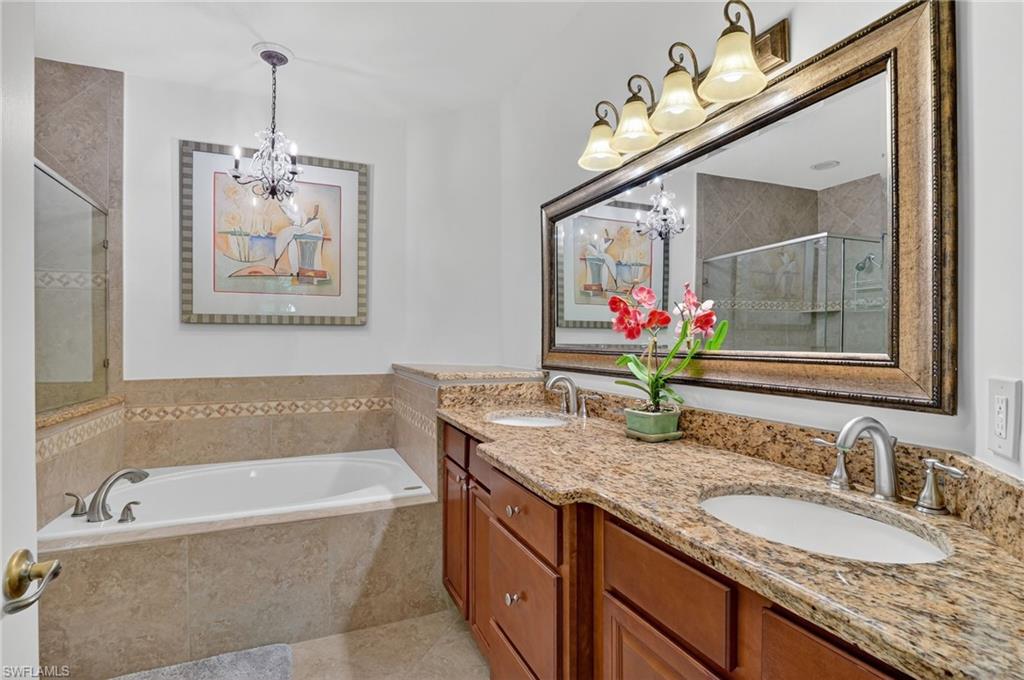 7092 Timberland Circle, Unit 201 Naples, FL 34109 - Photo 38 of 43 a bathroom with a granite countertop tub a double vanity sink and a mirror
