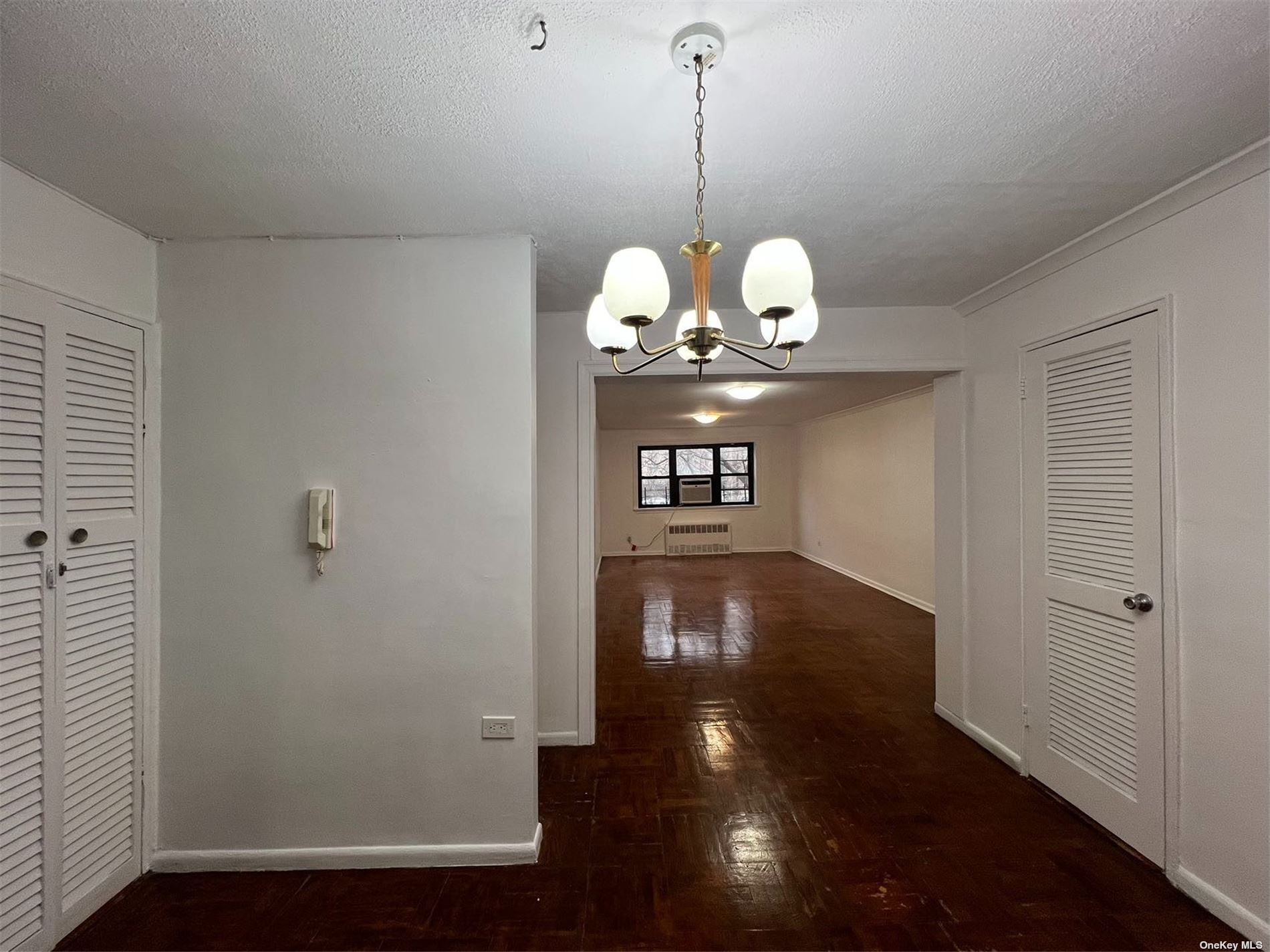 a view of a hallway with wooden floor and chandelier