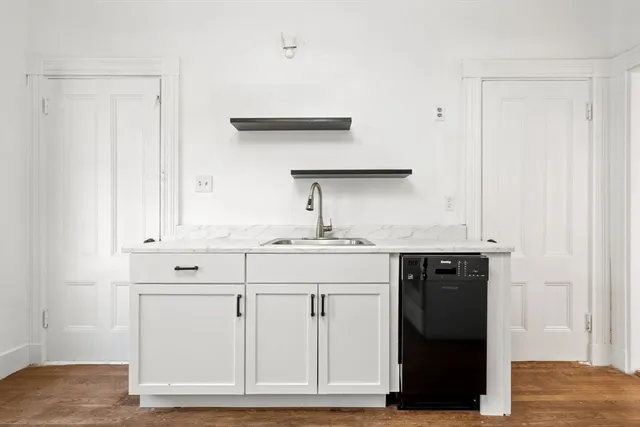 a kitchen with white cabinets and sink