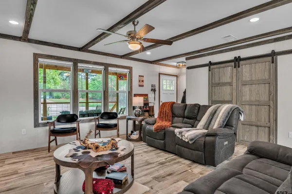 a living room with furniture kitchen view and large windows