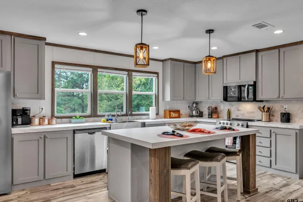 a kitchen with a stove a sink a center island and cabinets