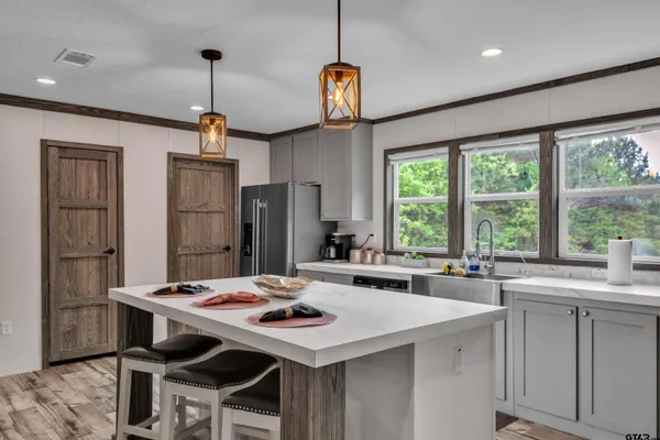 a kitchen with stainless steel appliances kitchen island a table chairs sink and wooden floor