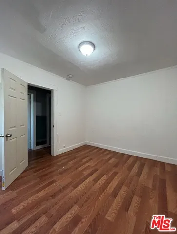 a view of an empty room with wooden floor and closet