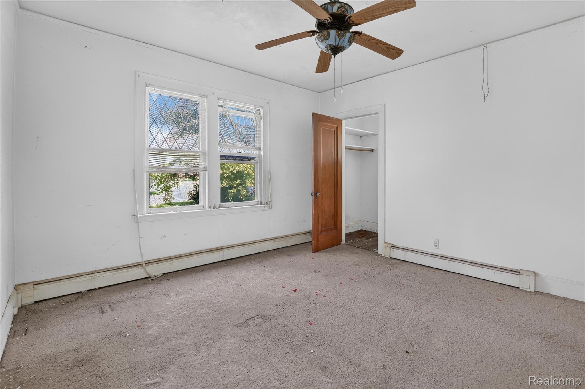26275 Pennsylvania Road Romulus, MI 48174 - Photo 15 of 23 Room featuring a ceiling fan, a window with diamond-patterned grilles, a wood-panel door, and a built-in closet with shelving