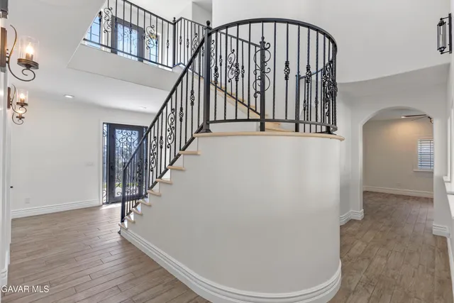 a large kitchen with stainless steel appliances kitchen island granite countertop a refrigerator a sink dishwasher a stove with white cabinets and wooden floor