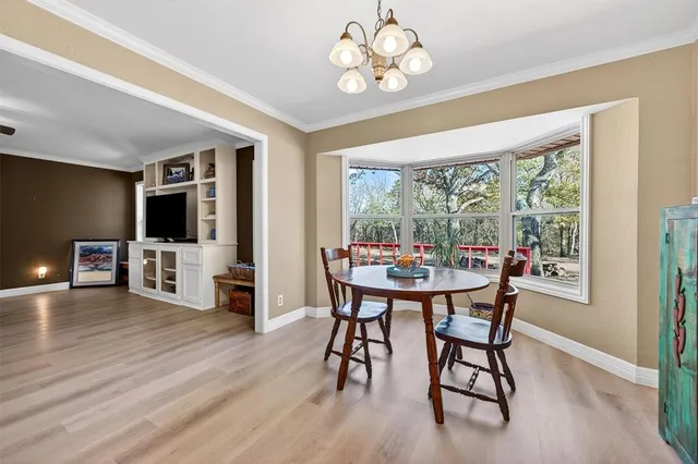 a kitchen with stainless steel appliances kitchen island granite countertop a stove top oven a sink a dining table and chairs with wooden floor