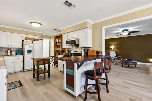 a kitchen with stainless steel appliances a stove a sink dishwasher a refrigerator and cabinets with wooden floor
