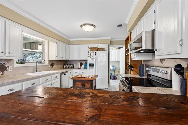 a kitchen with stainless steel appliances granite countertop a refrigerator a sink dishwasher a stove and a dining table with wooden floor