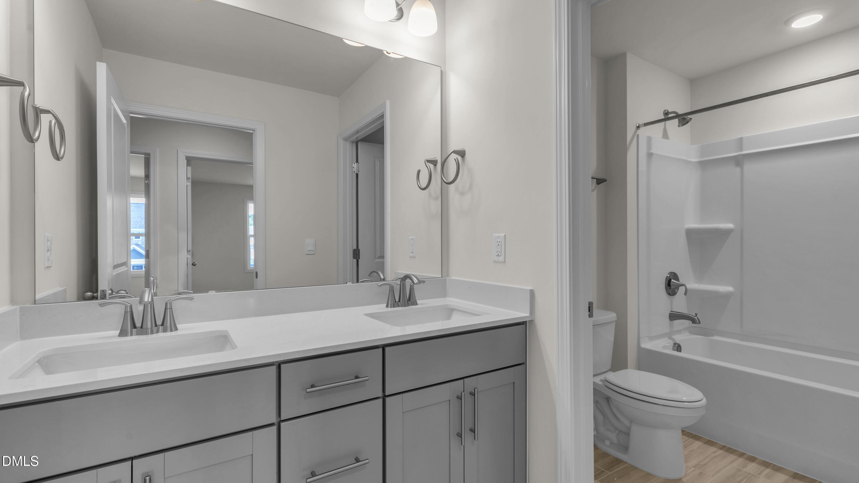 191 Gilmer Street Fuquay-Varina, NC 27526 - Photo 27 of 40 a bathroom with a sink a toilet and a large mirror