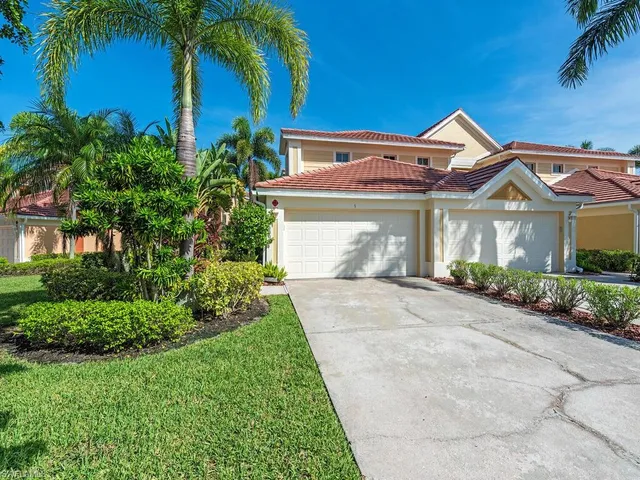 a front view of a house with a garden and palm trees